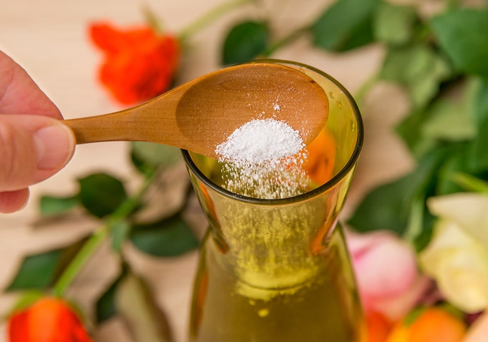 Delicately mixing the contents of a packet of flower food into a vase