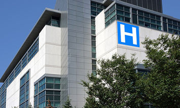 A large, modern hospital building with many windows; a prominent blue 